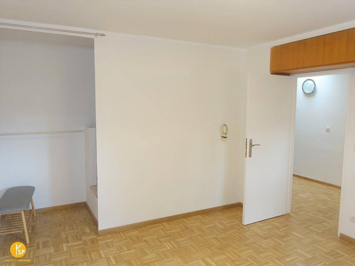 Leerer Raum mit hellem Holzparkettboden und weiß gestrichenen Wänden, bereit zur Einrichtung.
