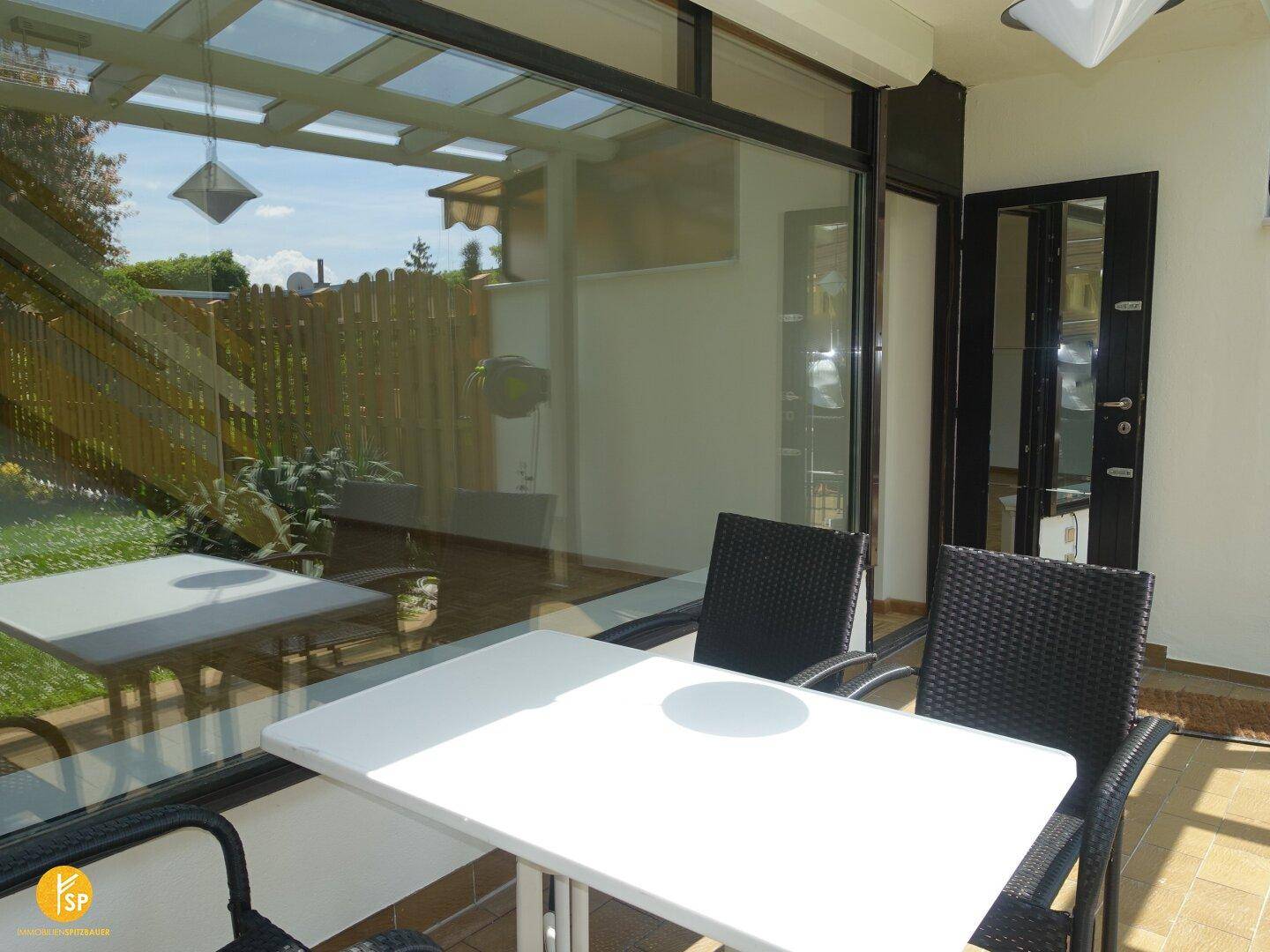 Überdachte Terrasse mit Esstisch und Stühlen, die einen Blick in den Garten bietet.