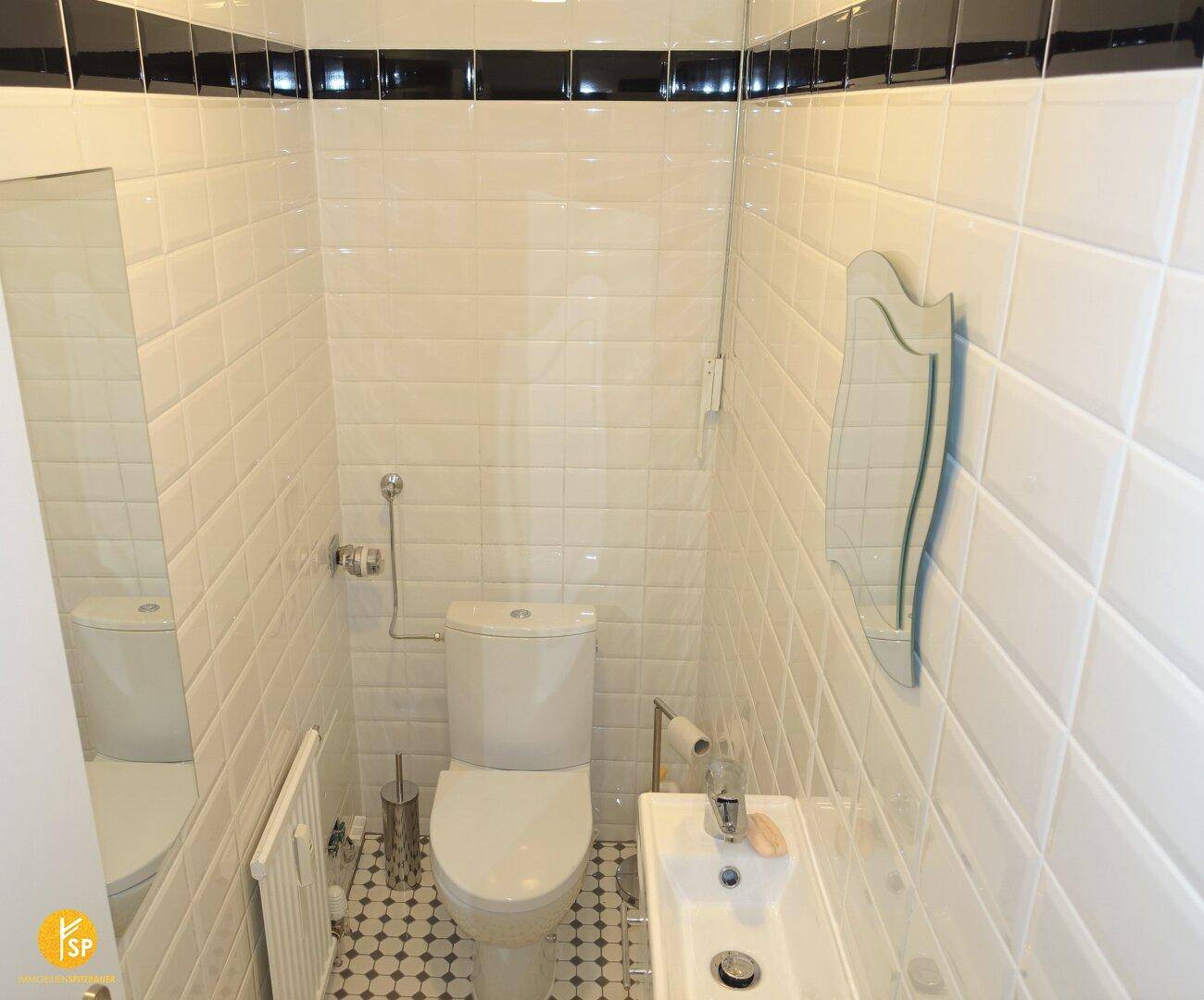 Kleines, hell gefliestes Gäste-WC mit modernem Waschbecken und Toilette.