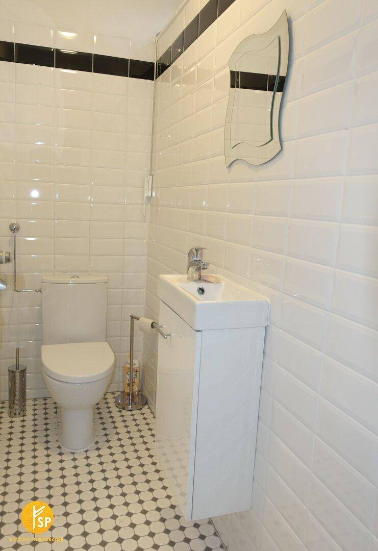 Modern gefliestes Gäste-WC mit kleinem Waschbecken und Wand-WC.