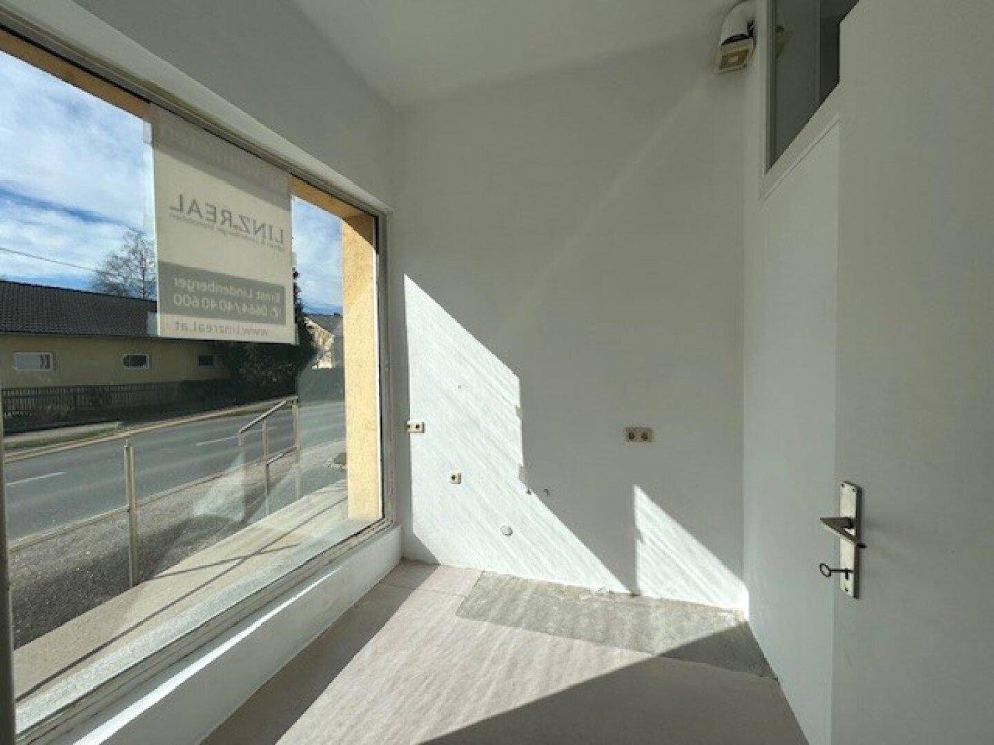 Kleiner, heller Raum mit großer Fensterfront zur Straße, ideal für ein Ladengeschäft oder Büro, mit viel Tageslicht.