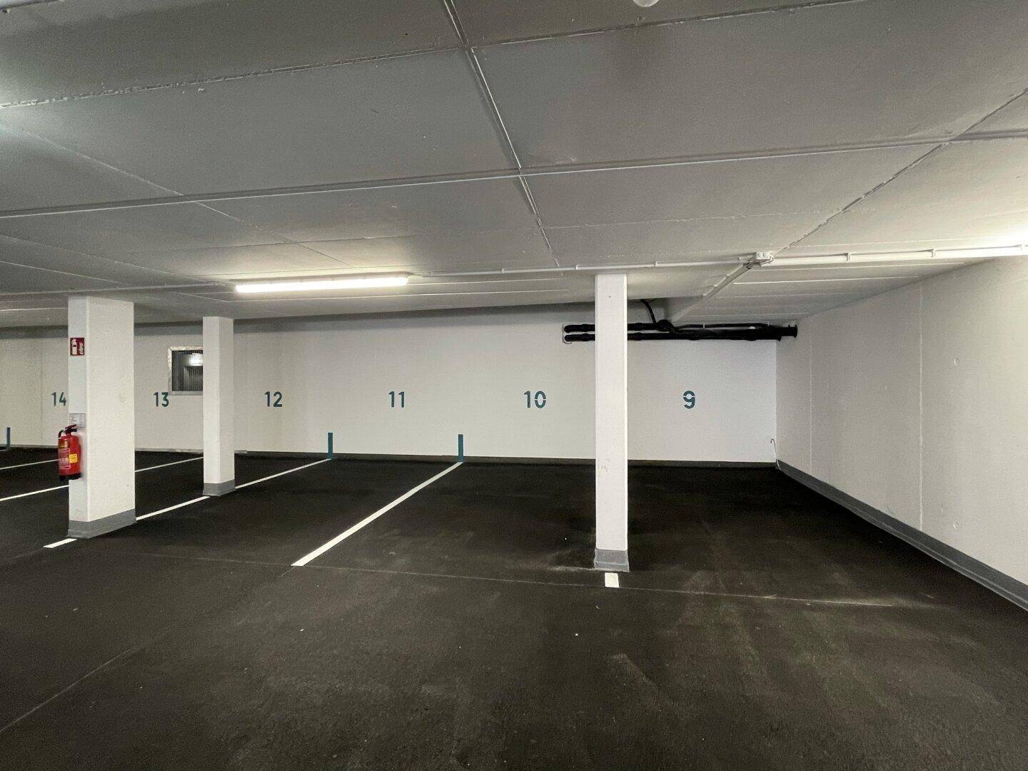 Geräumige Tiefgarage mit markierten Stellplätzen und guter Beleuchtung für mehrere Fahrzeuge.
