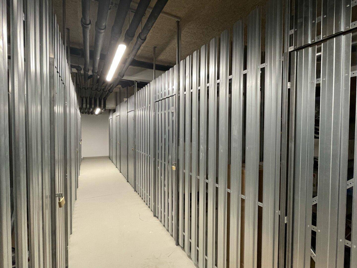 Kellerabteile mit Metallwänden bieten zusätzlichen Stauraum für Bewohner im Untergeschoss.