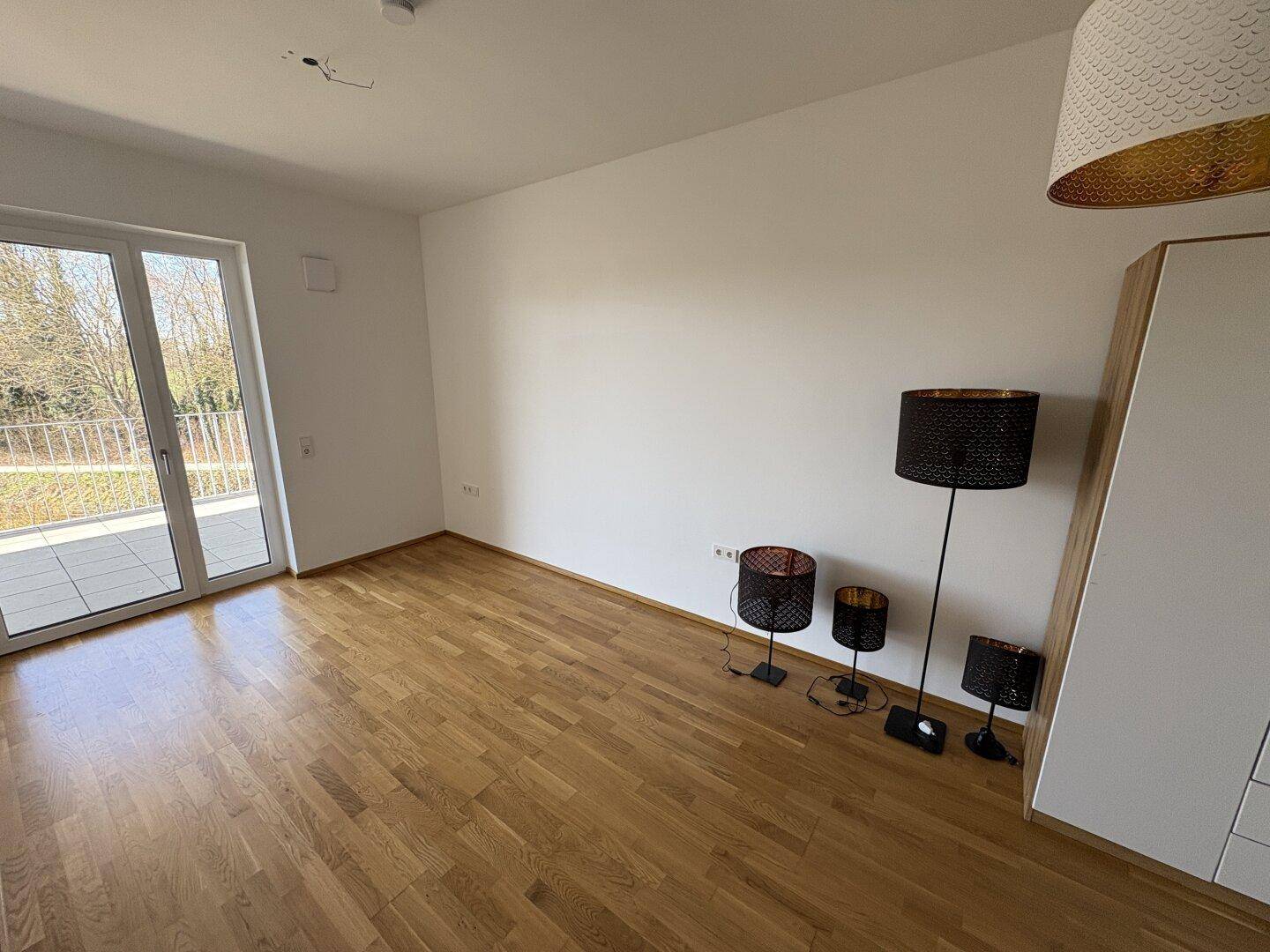 Geräumiger, heller Raum mit Parkettboden und direktem Zugang zu einer großen Terrasse.