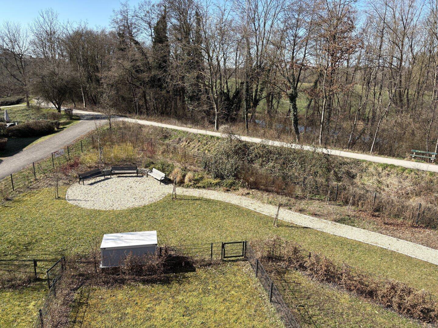 Panoramablick auf eine weitläufige Grünfläche mit Bäumen und Sitzgelegenheiten von oben.