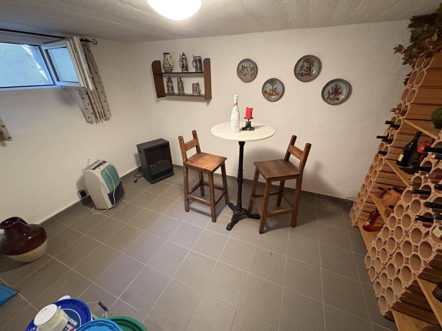 Gemütlicher Kellerraum mit Weinflaschenregalen, Bartisch und Fliesenboden.