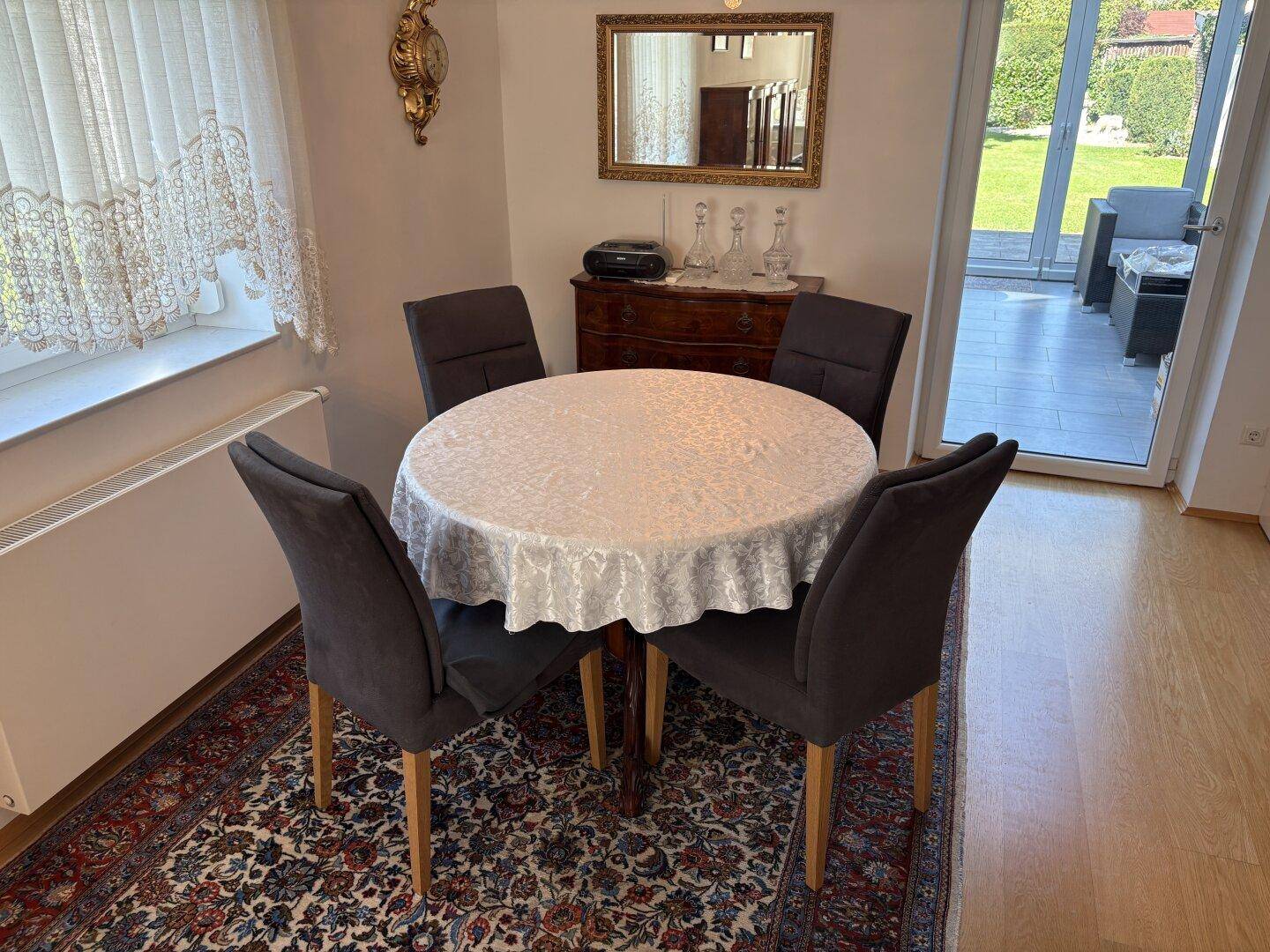 Gemütlicher Essbereich mit rundem Tisch, Teppich und Zugang zum Wintergarten.