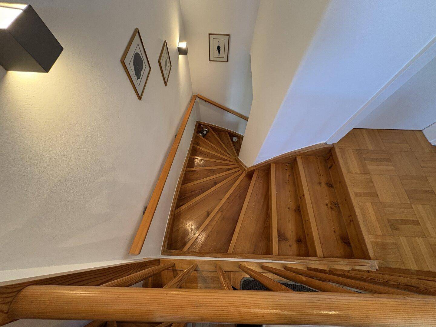 Holztreppe mit Geländer, die die verschiedenen Etagen des Hauses verbindet.