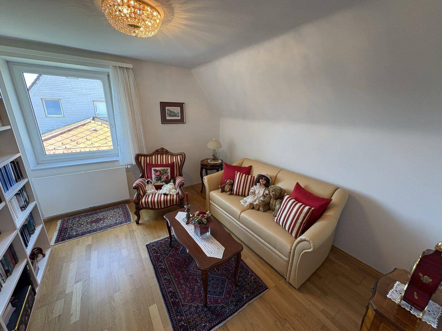 Gemütliches Zimmer im Dachgeschoss mit Sofa, Sessel und Blick nach draußen.