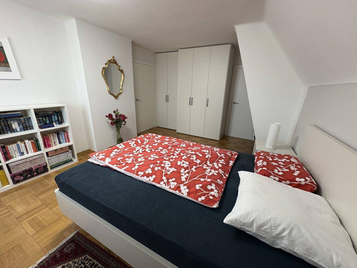 Schlafzimmer mit Einbauschränken, Parkettboden und einem großen Bett.