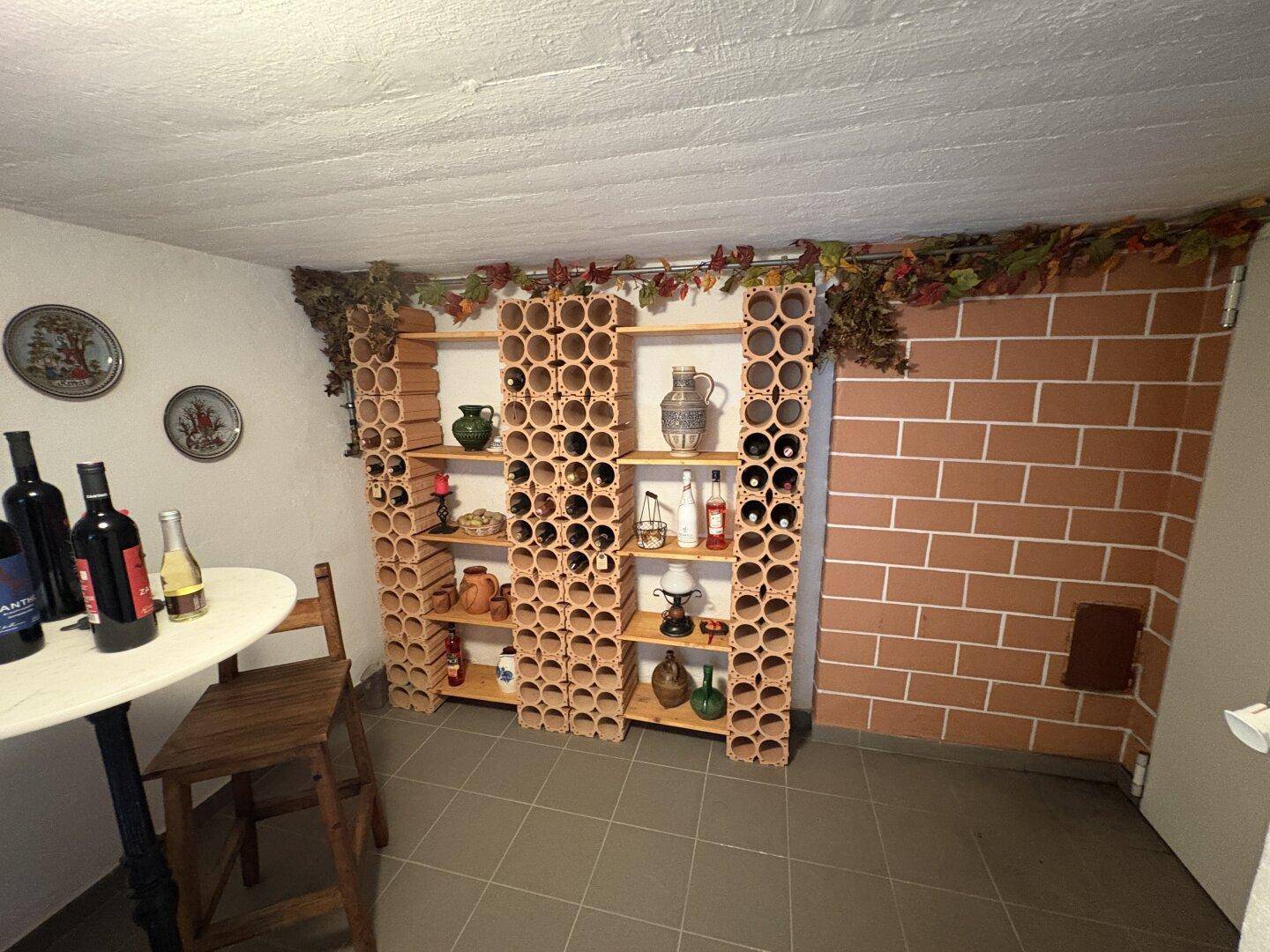 Kellerraum mit umfangreichen Weinregalen aus Terrakotta und rustikaler Wandgestaltung.