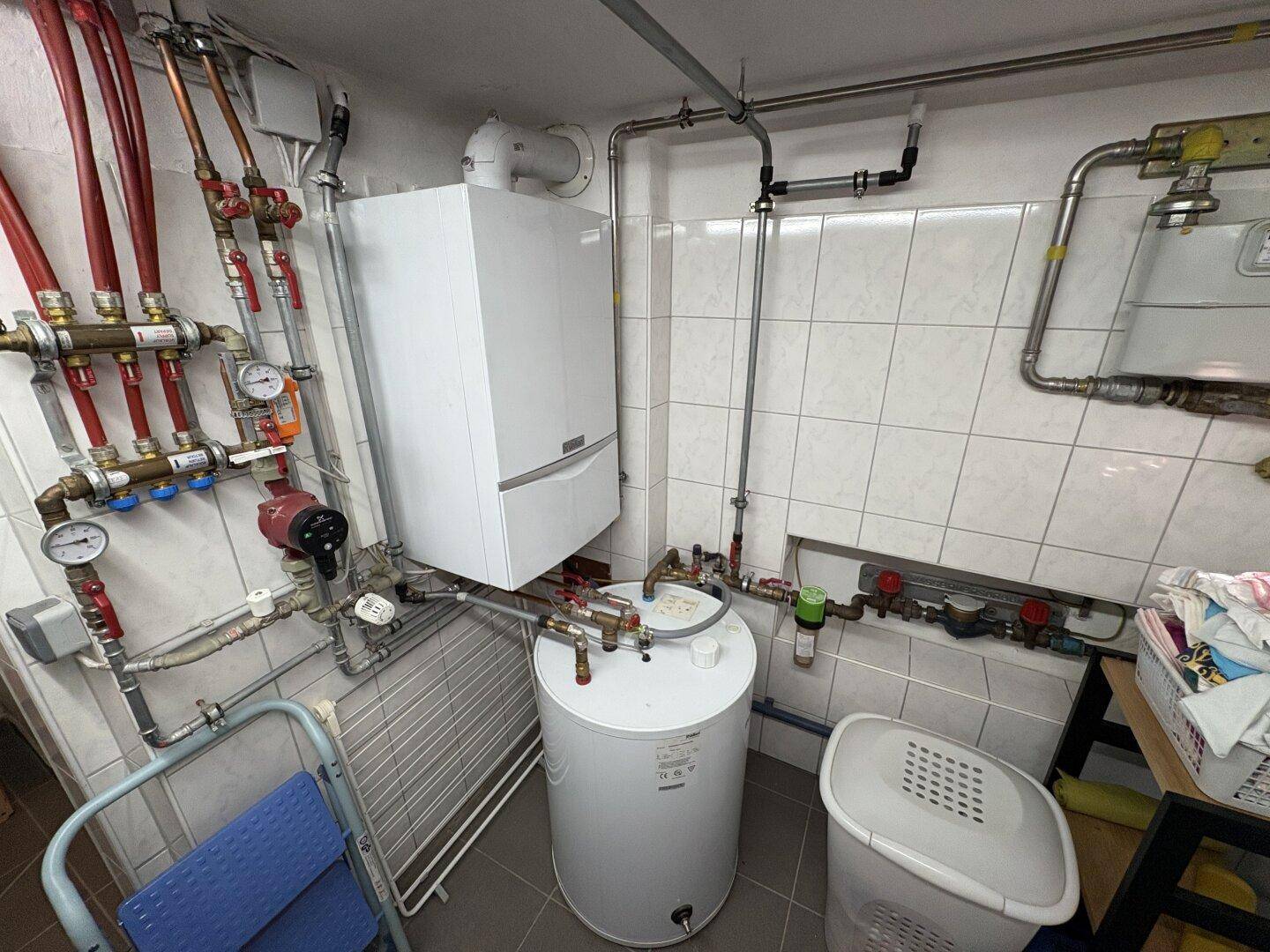 Heizungsraum im Keller mit moderner Heizungsanlage und Warmwasserspeicher.