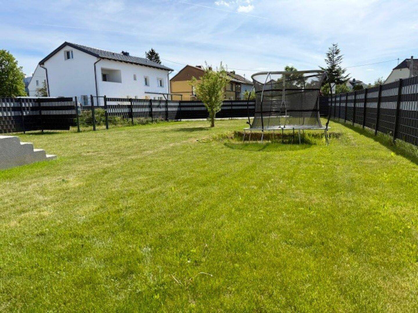 Gepflegter Garten mit Rasenfläche, Trampolin und Blick auf das Einfamilienhaus.