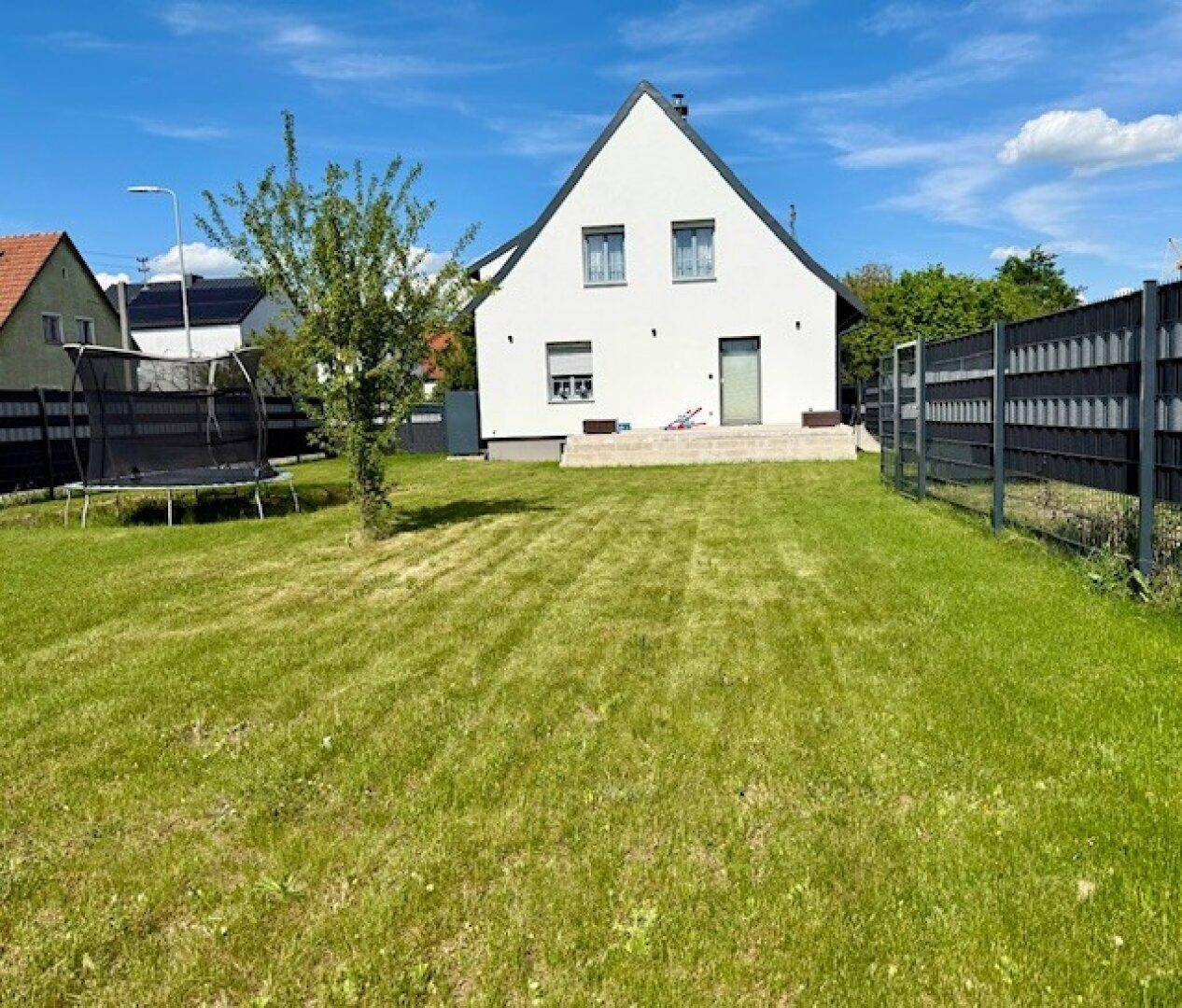 Weitläufiger Garten mit gepflegtem Rasen und Trampolin, ideal für Familienaktivitäten.