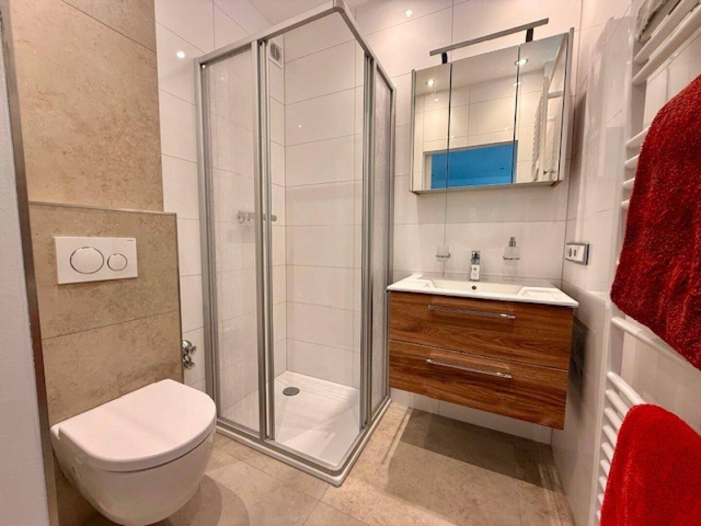 Modernes Badezimmer mit Duschkabine, Wand-WC, Holzwaschtisch und beheiztem Handtuchhalter.