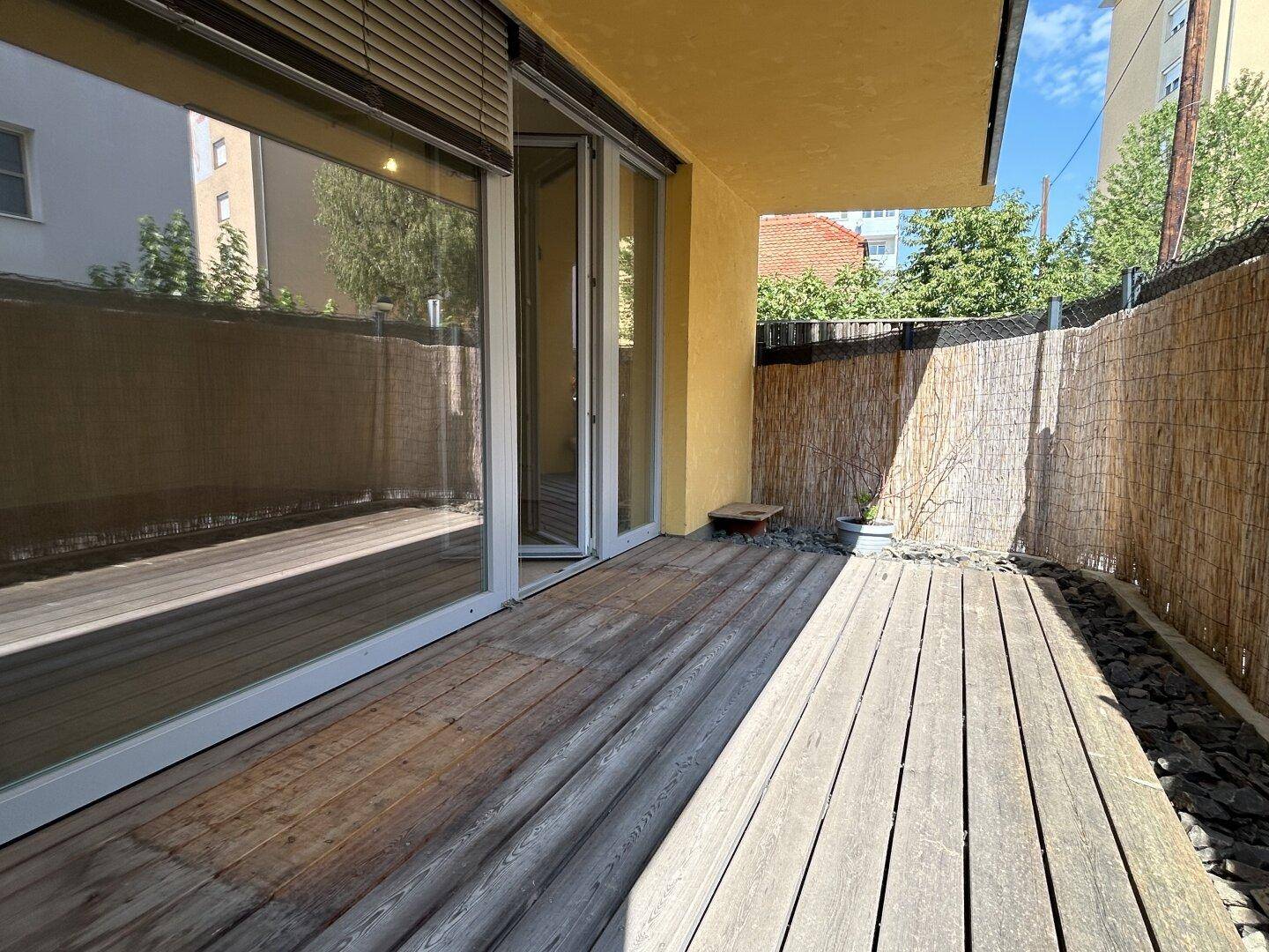 Geräumige Holzterrasse mit Sichtschutz und direktem Zugang zum Innenbereich der Wohnung.
