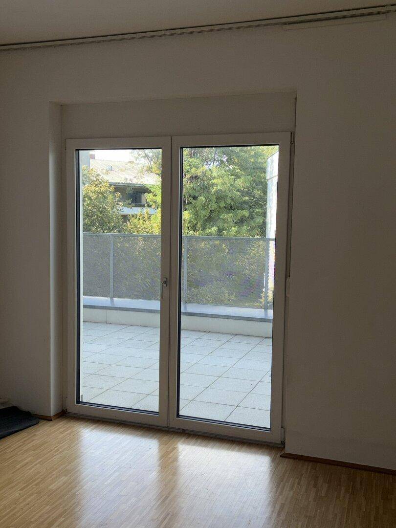 Lichtdurchfluteter Wohnbereich mit Parkettboden und großem Fenster zur Terrasse.