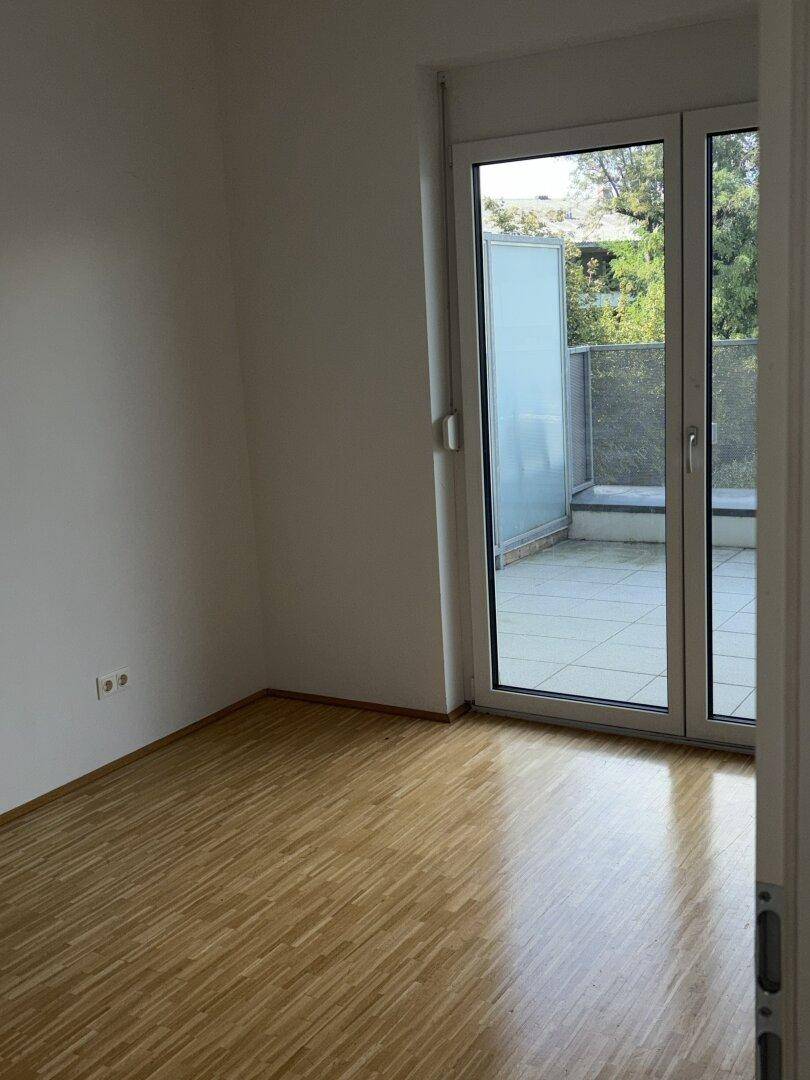 Schlafzimmer mit Parkettboden und direktem Zugang zu einer privaten Terrasse.