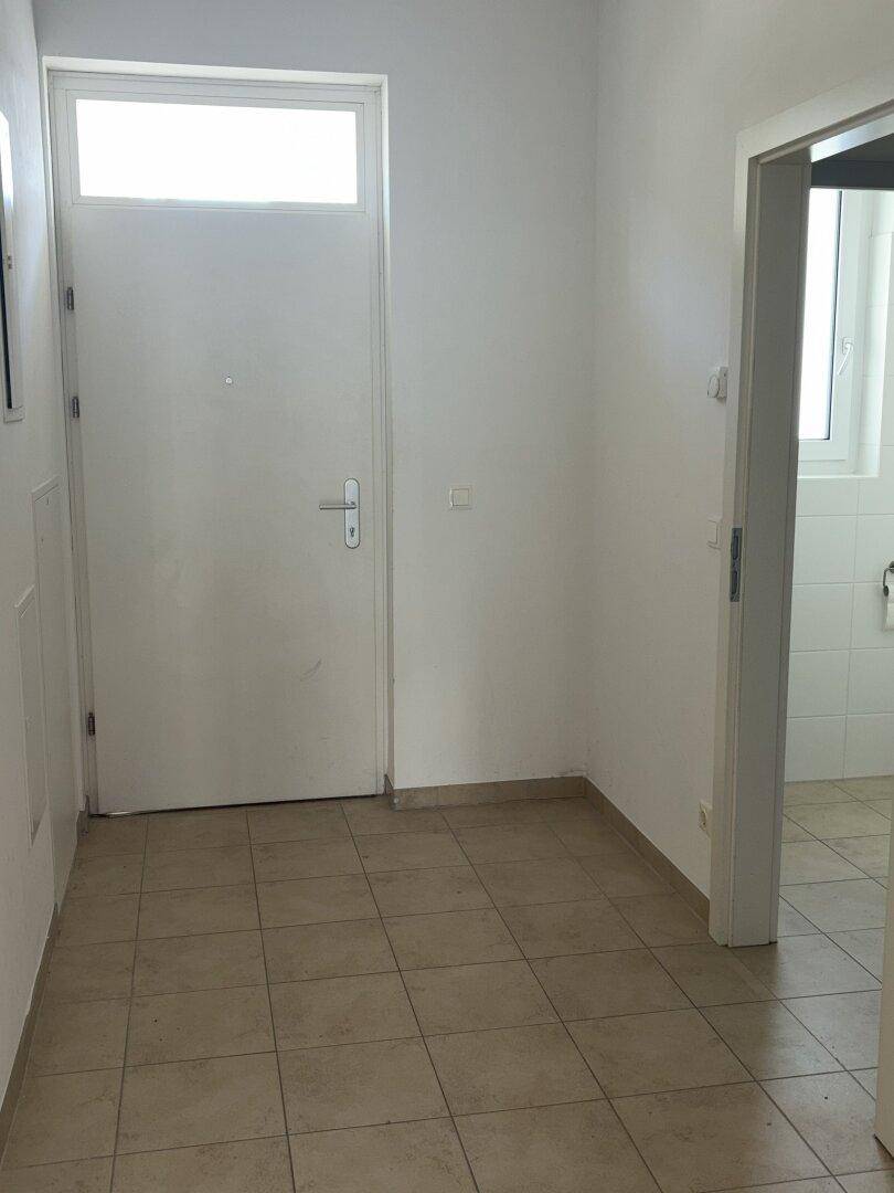 Eingangsbereich mit Fliesenboden und Zugang zu weiteren Räumen und dem Badezimmer.