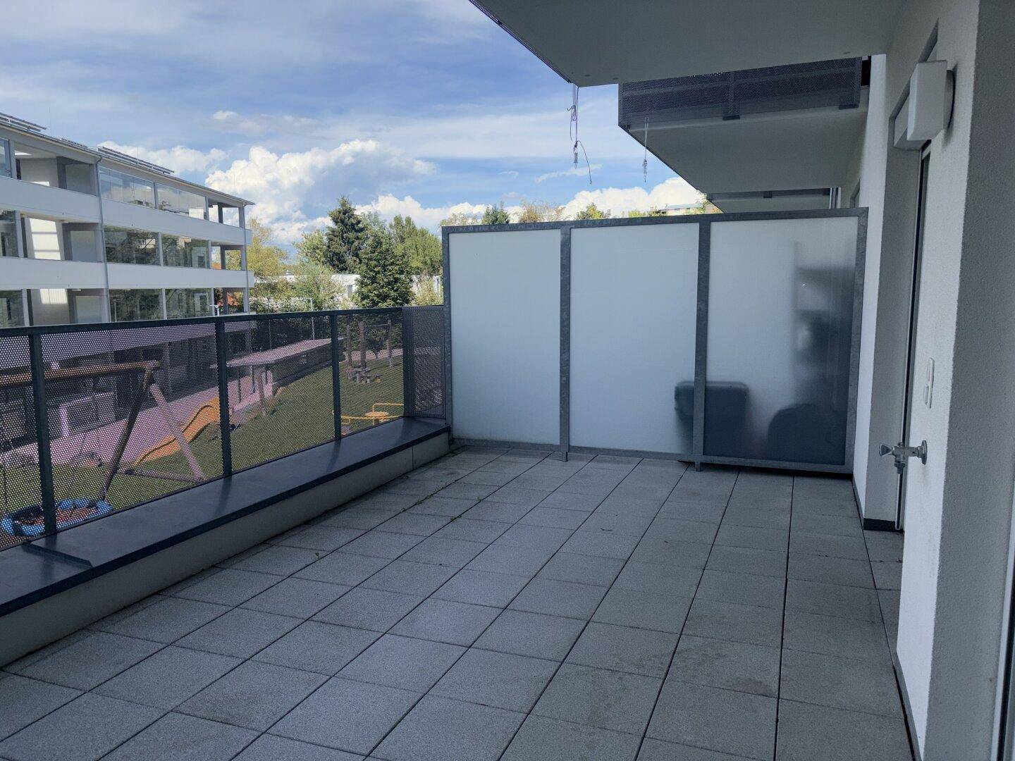 Große Terrasse mit Sichtschutz und Blick auf die umliegenden Gebäude und Grünflächen.