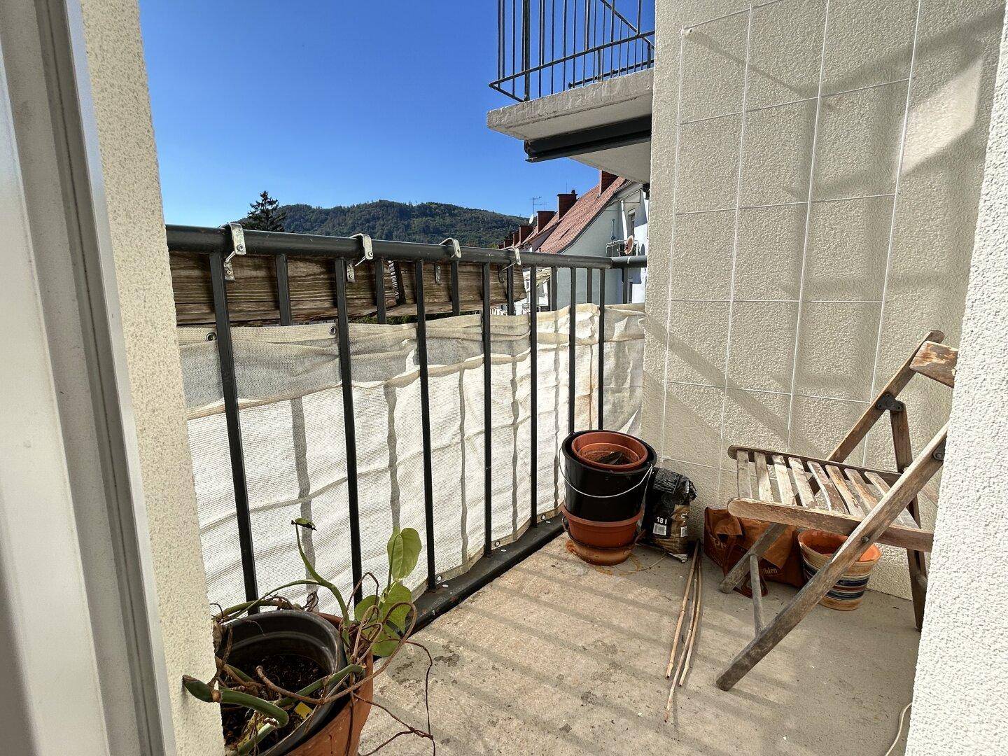 Kleiner Balkon mit Bergblick, Pflanzen und einem Holzstuhl für entspannte Stunden.