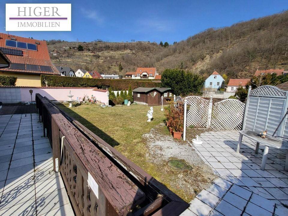 Überblick über den Garten und die Terrasse mit Blick auf die umliegende Natur und Nachbarhäuser.