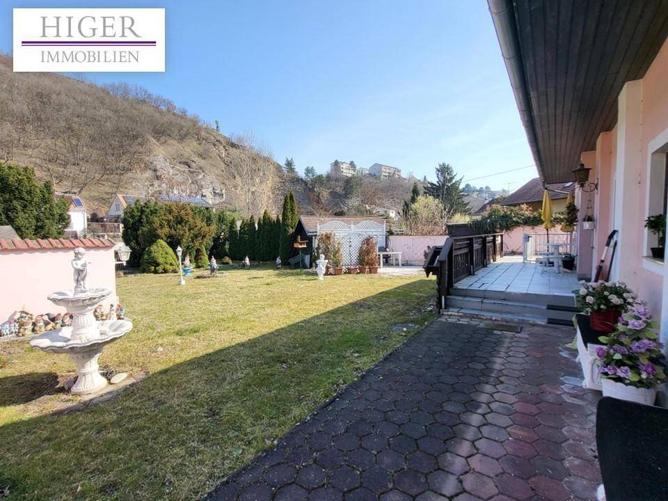 Weitläufiger Garten mit Rasenfläche, Zierbrunnen und Zugang zur Terrasse des Hauses.