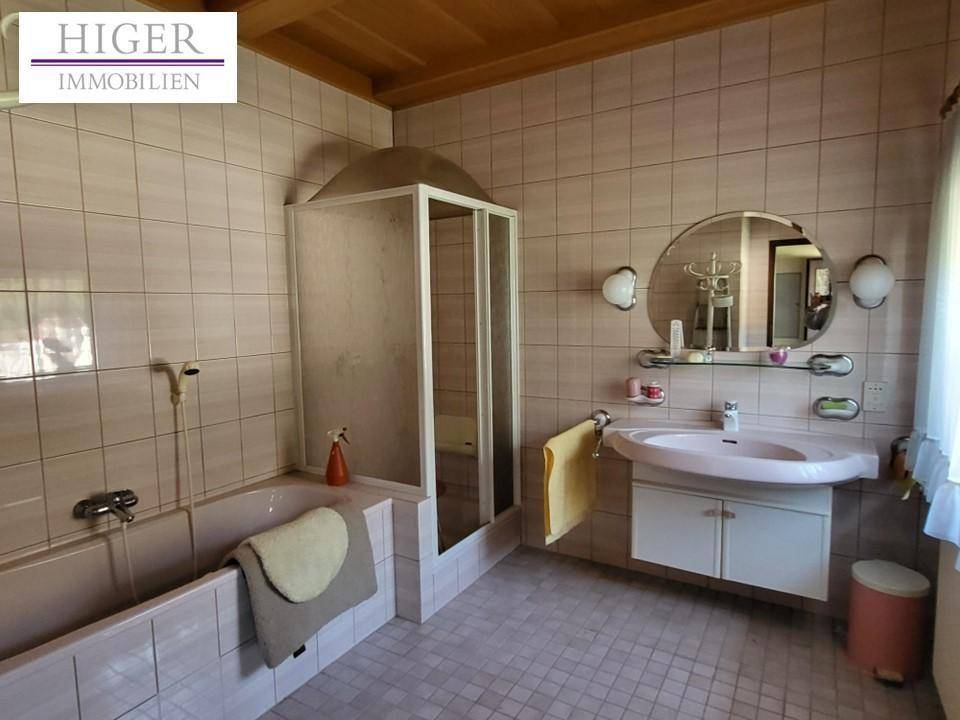 Badezimmer im 80er-Jahre-Stil mit rosa Fliesen, Badewanne und Duschkabine.