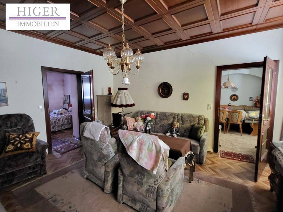 Gemütliches Wohnzimmer mit Kassettendecke, traditionellen Möbeln und Kronleuchter.