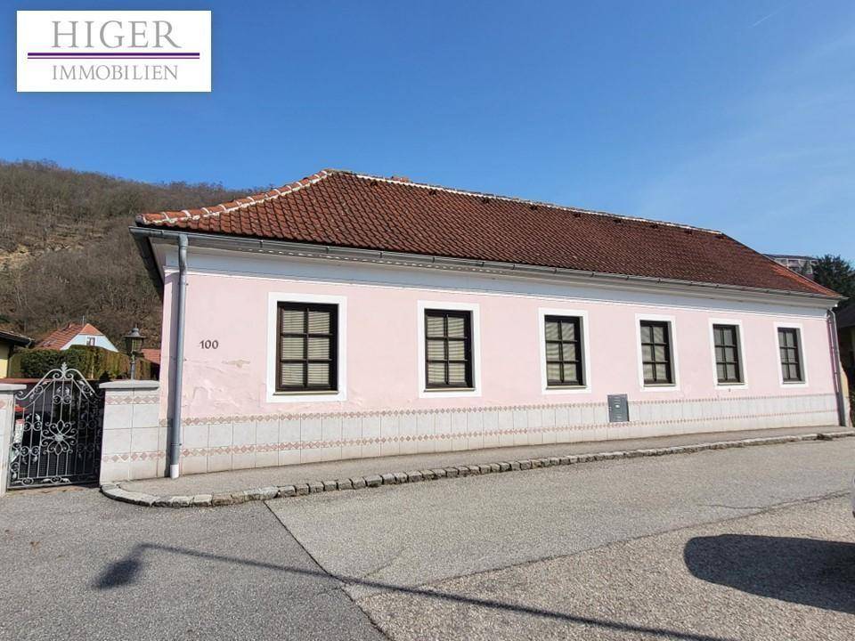 Seitenansicht des rosa gestrichenen Hauses mit traditionellem Ziegeldach und Fenstern zur Straße.