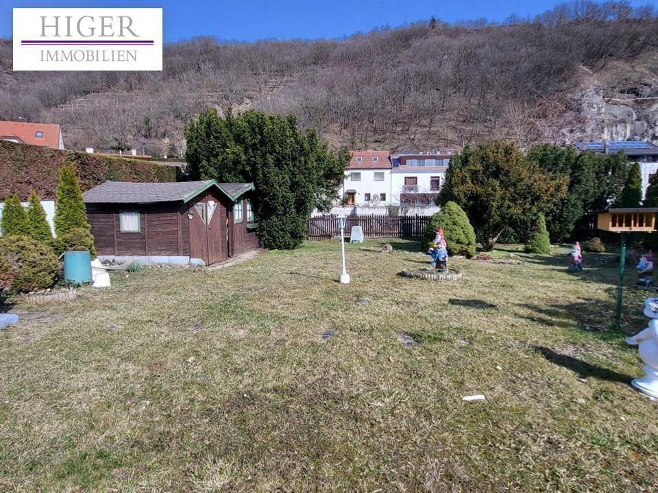 Großer Gartenbereich mit Rasen, Gartenhaus und Blick auf die umliegende Hügellandschaft.