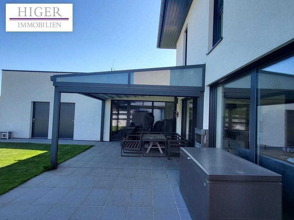 Geräumige, überdachte Terrasse mit Outdoor-Möbeln und Zugang zum Garten.