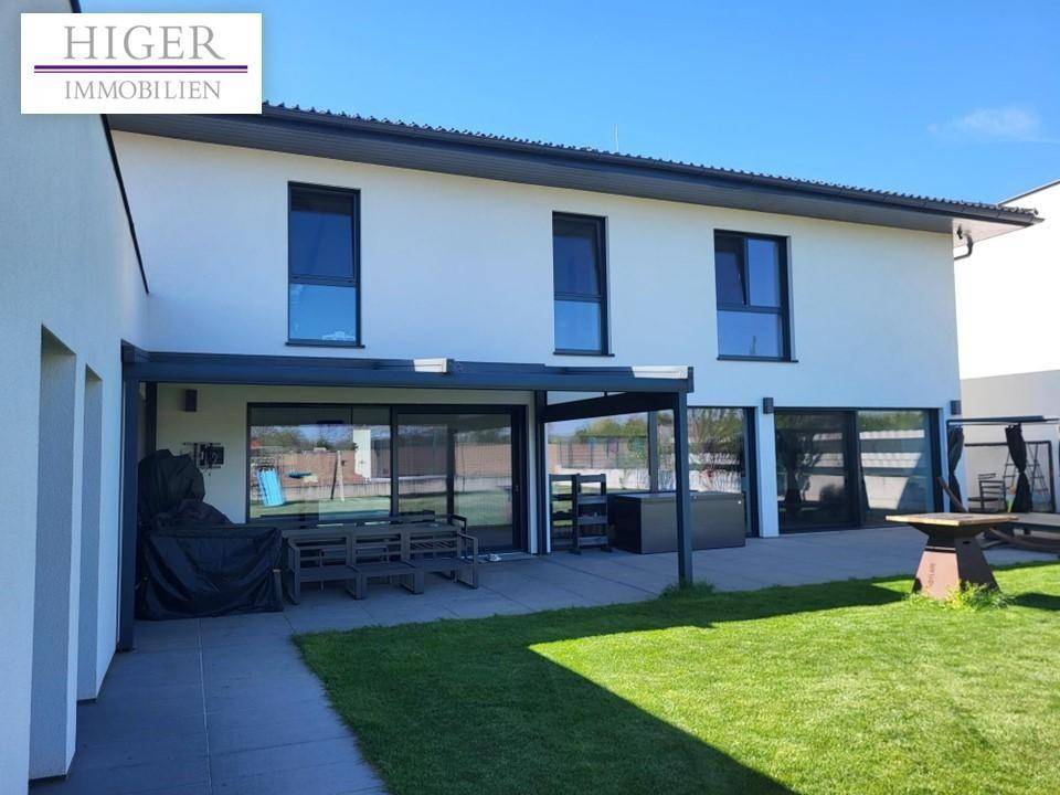 Weitläufige Terrasse mit Gartenmöbeln und Blick auf die Rasenfläche des Gartens.