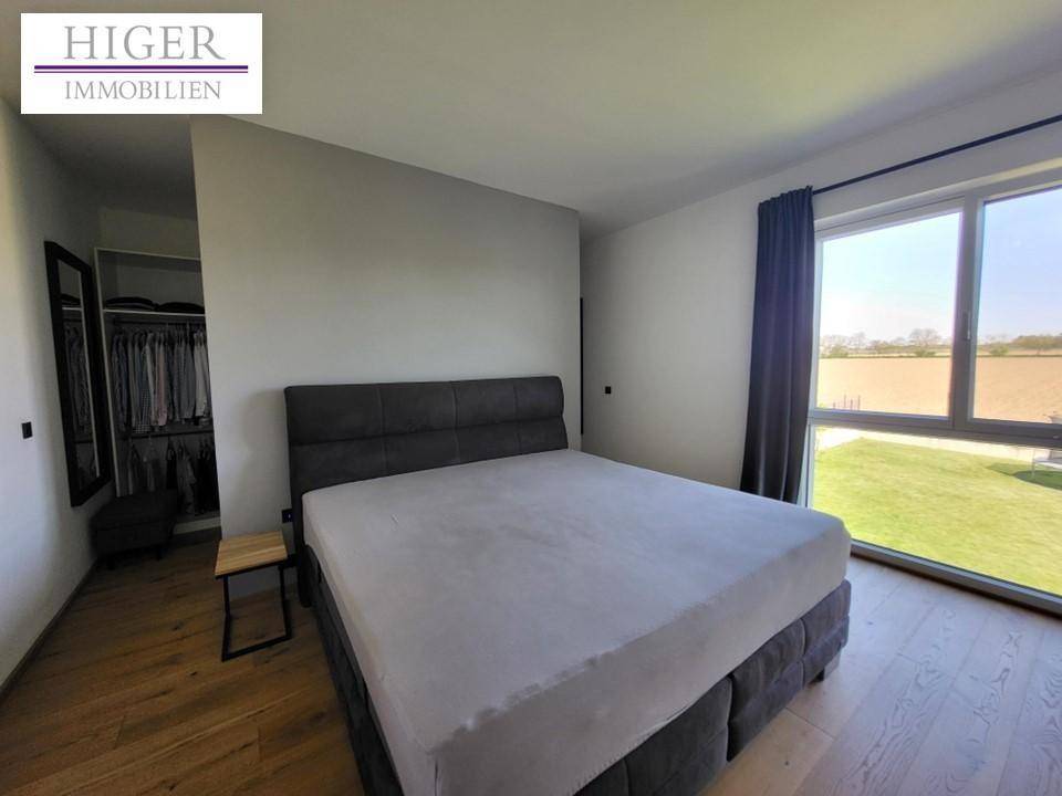 Schlafzimmer mit Doppelbett, Holzboden und großem Fenster mit Blick ins Grüne.