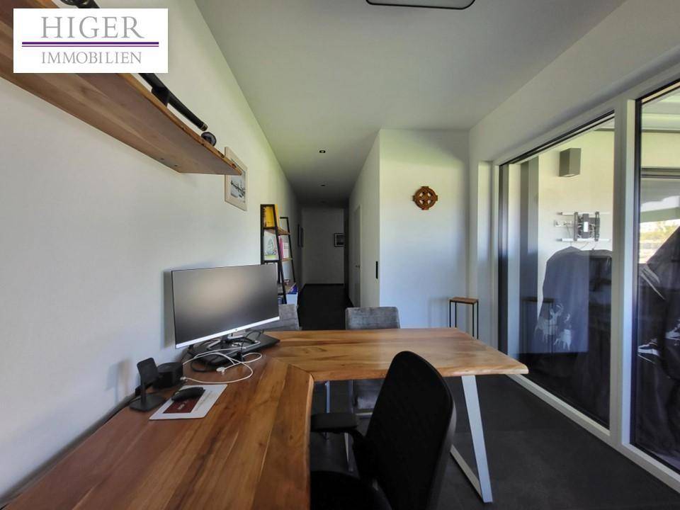 Langer Flur mit Arbeitsbereich, Holztisch und großen Fenstern, die viel Licht hereinlassen.