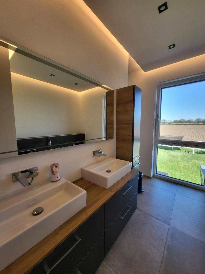 Modernes Badezimmer mit Doppelwaschbecken, Spiegelschrank und Fenster mit Weitblick.