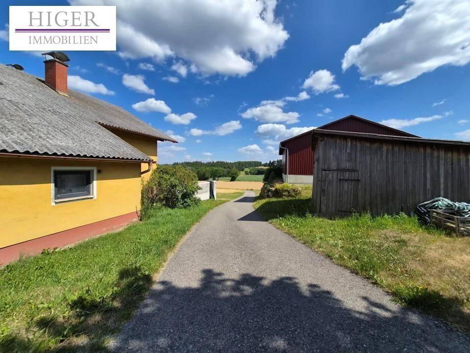 Ländliches Anwesen mit Wohnhaus, Nebengebäude und Zufahrt, umgeben von Feldern.