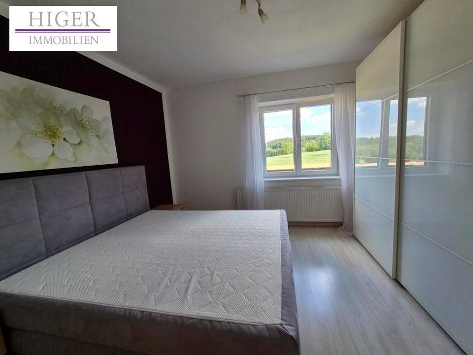 Schlafzimmer mit Bett, großem Kleiderschrank und Blick ins Grüne.