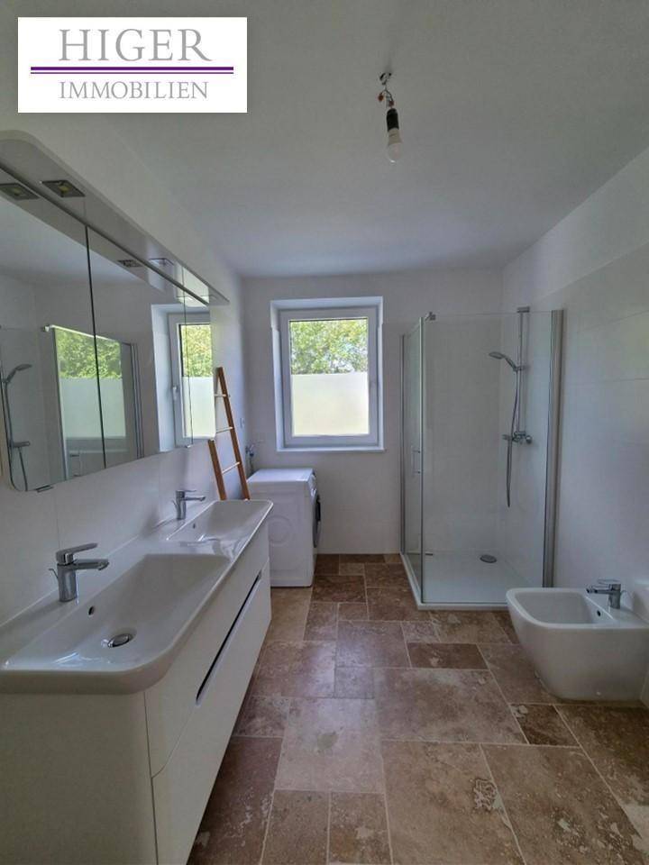Geräumiges Badezimmer mit Doppelwaschbecken, Dusche, Bidet und Fenster.