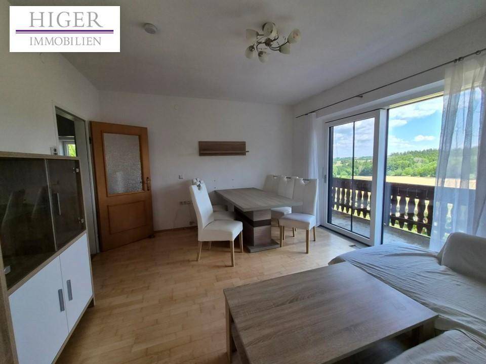 Gemütlicher Wohn-Essbereich mit Holzboden und Zugang zu einem Balkon mit Weitblick.