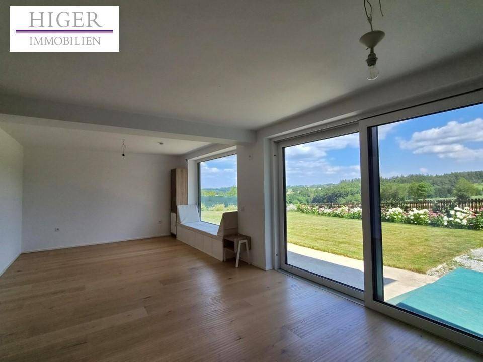 Heller Wohnbereich mit Holzboden, großen Fenstern und direktem Zugang zum Garten.