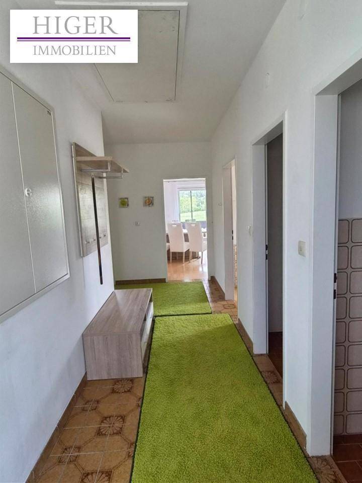 Flur mit grünen Läufern, Garderobe und Blick in den Essbereich.