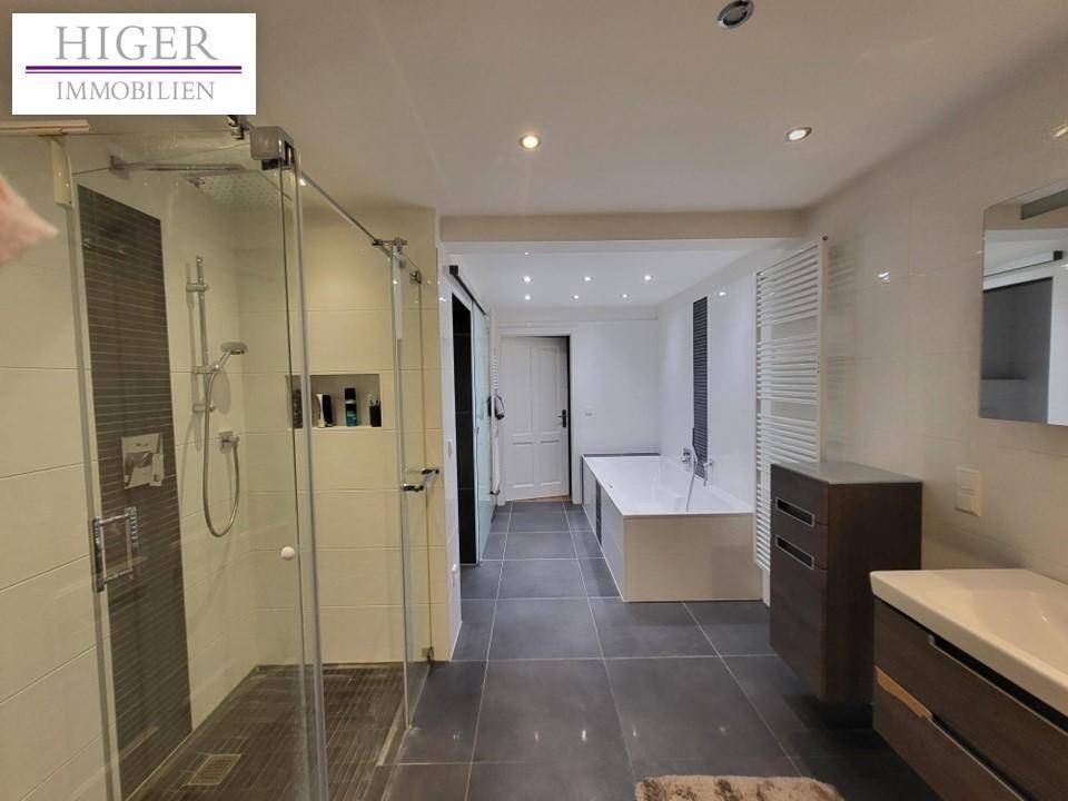 Modernes Badezimmer mit großer begehbarer Dusche, Badewanne und Einbauspots.