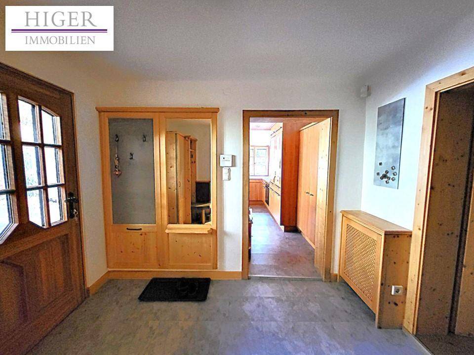 Heller Eingangsbereich mit Holztür, Garderobenschrank und Zugang zur Küche.