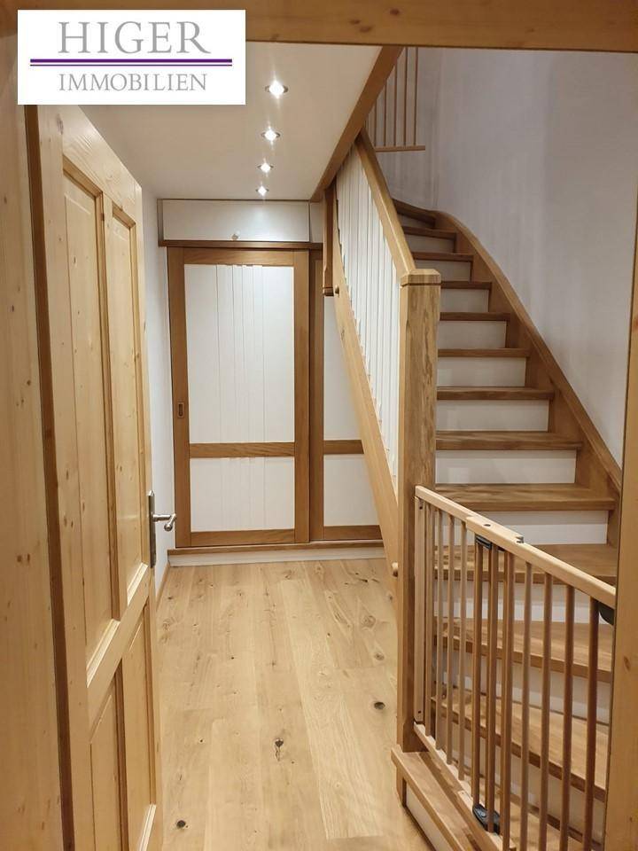 Eingangsbereich mit Holztreppe, Einbauschrank und Holzboden, hell und einladend.