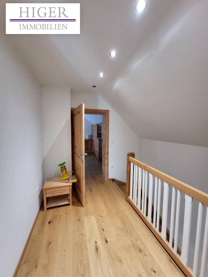Heller Flur im Dachgeschoss mit Holzgeländer, Holzboden und Dachschräge.