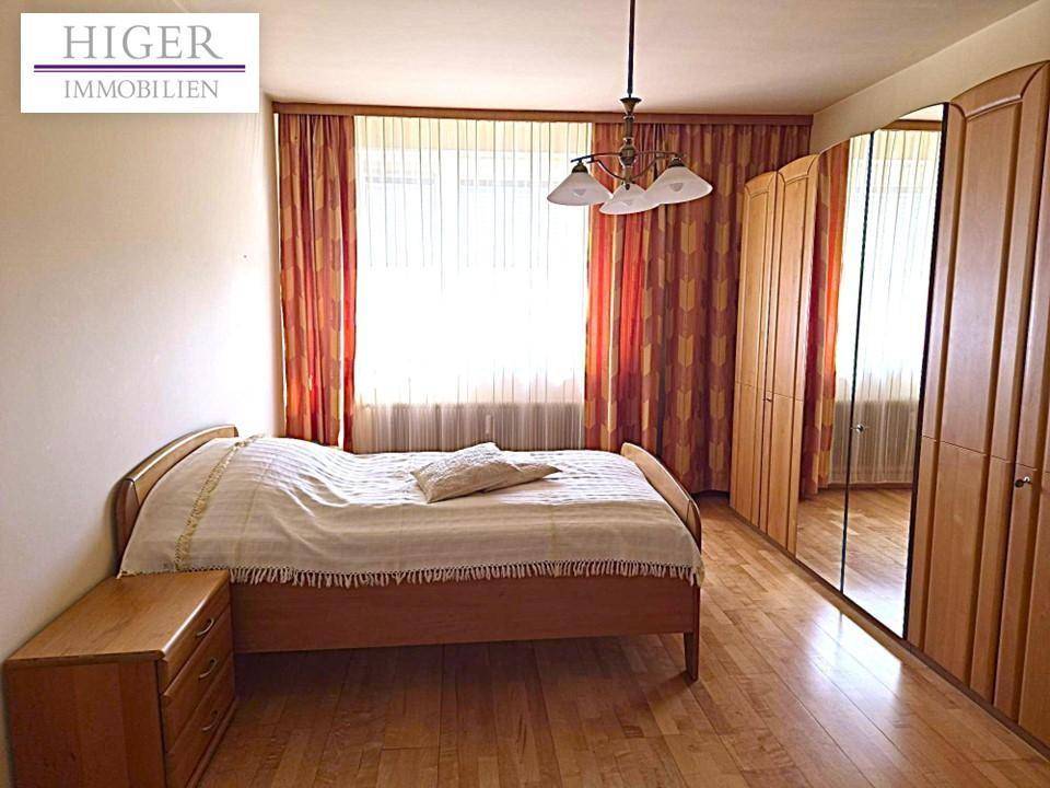 Helles Schlafzimmer mit Holzboden, Doppelbett und großem Spiegelschrank entlang der Wand.