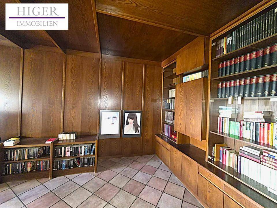 Gemütliche Bibliothek mit holzvertäfelten Wänden, eingebauten Bücherregalen und Fliesenboden.