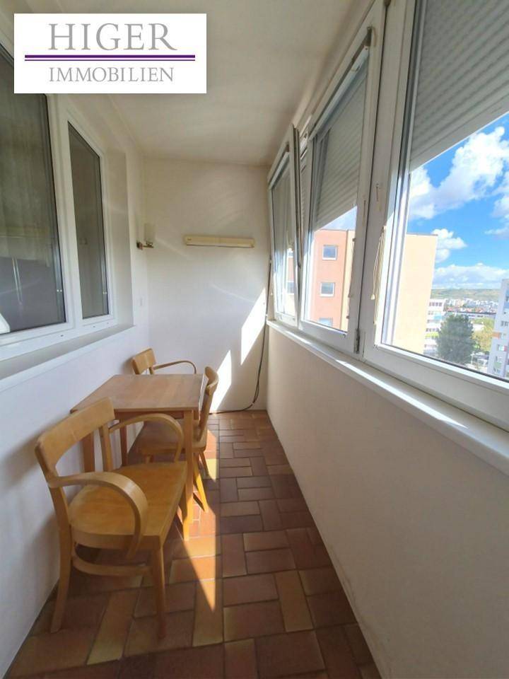 Verglaste Loggia mit Fliesenboden und kleinem Tisch, bietet einen hellen, geschützten Außenbereich.