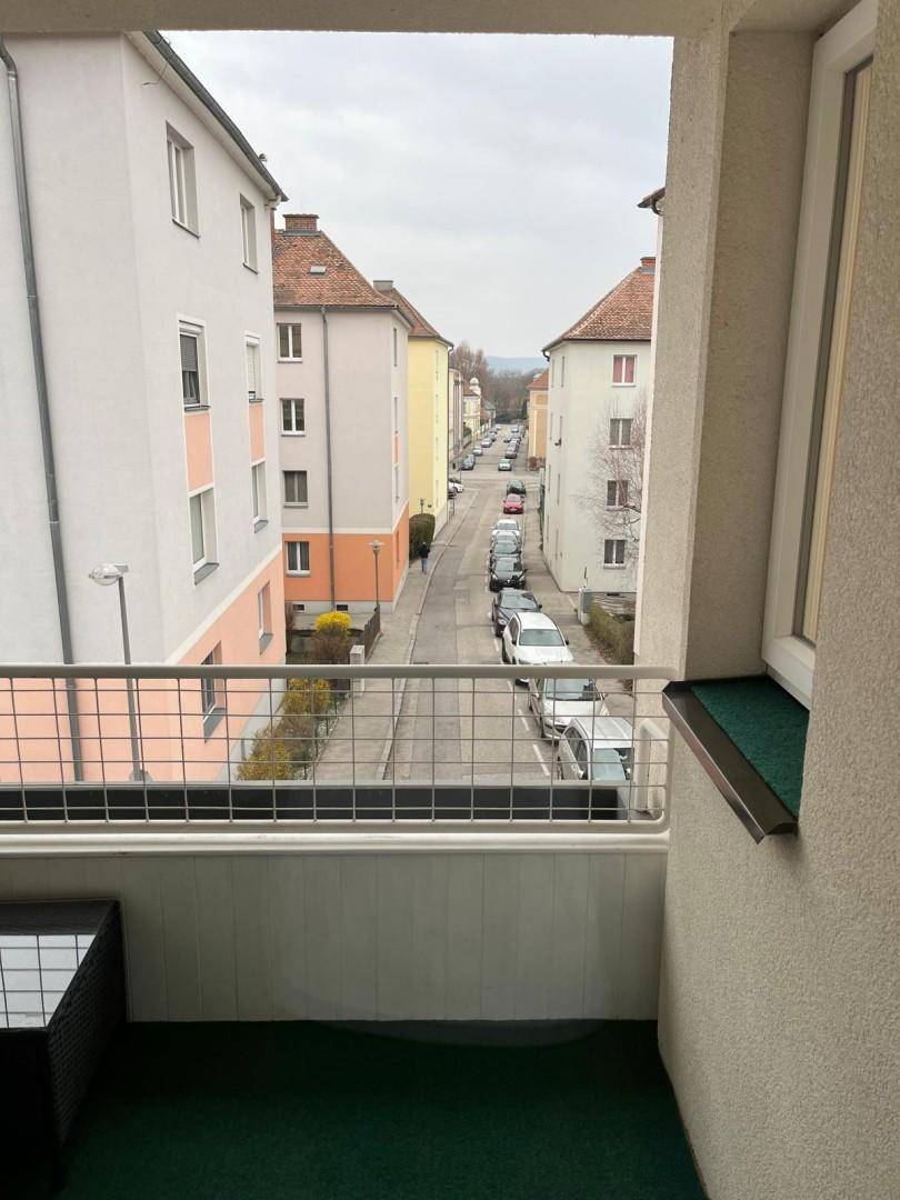 Balkon mit Blick auf die Straße und die umliegenden Gebäude der Wohngegend.